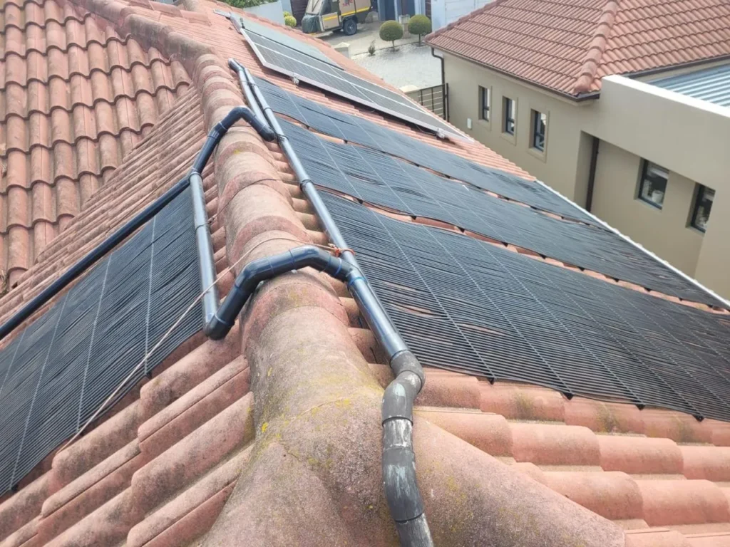 Solar pool heating panels on both sides of the roof ridge, joined by pipework